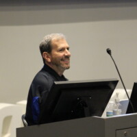 A presenter smiles at Compliance Jam workshop